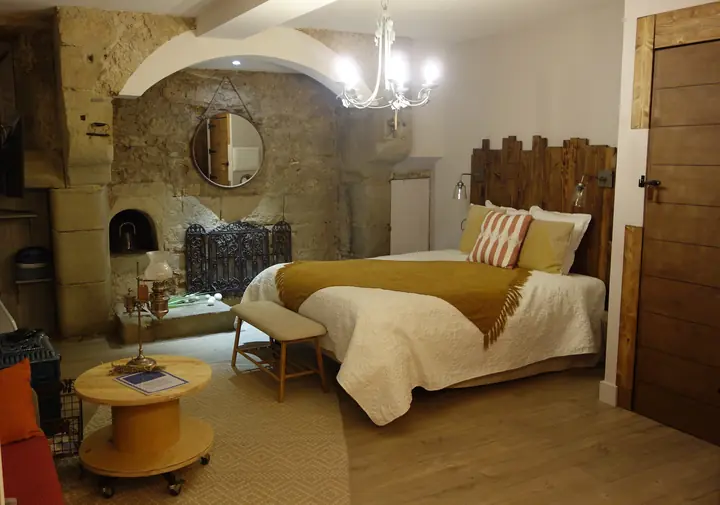 Vue générale du couchage et des voûtes en pierre — La Chaumière, hébergement Bed in Shop à Romans-sur-Isère