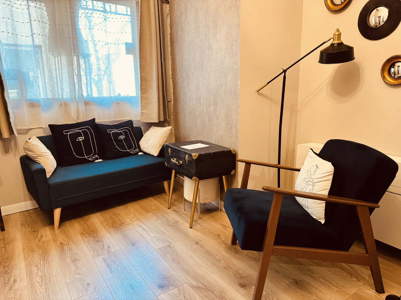 Le salon du Tailleur, avec son canapé bleu, son fauteuil et sa malle transformée en table.